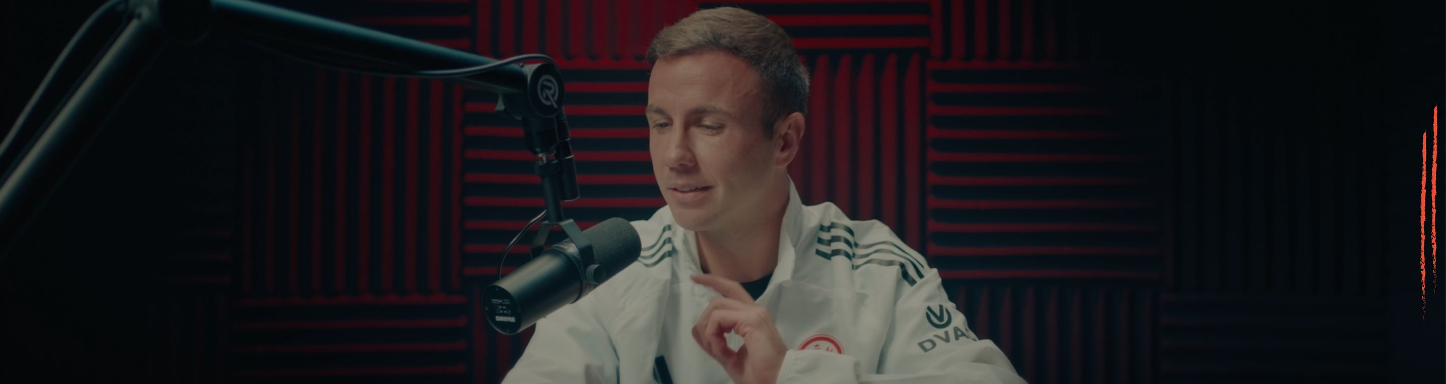 Fußballprofi am Podcast-Mikrofon vor rotem Akustikschaum